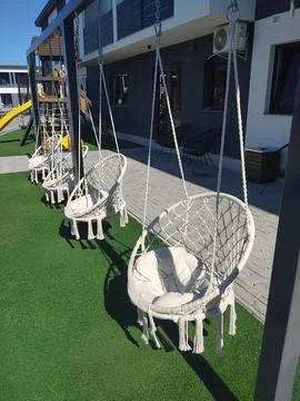 Row of modern macrame hanging swing chairs on a patio with artificial grass 写真素材