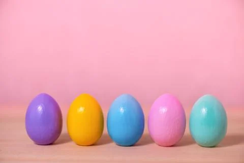 Row multi colored painted Easter eggs over pink background, festive greeting  Foto stock