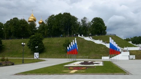Row of national Russian flags waving in wind in park with a church in background Stock Footage 99256906