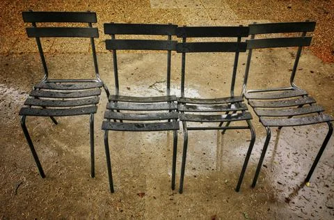 Row of old and rustic chairs in a public park Stock Photos