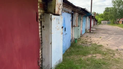 A row of old, multi-colored metal garage doors with rusty locks and brick  動画素材 337359923