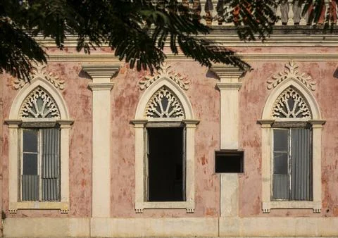Row of ornate Gothic-arched windows along a weathered colonial facade, Beng.. Stock Photos