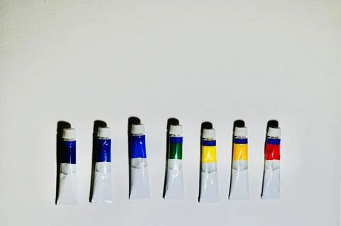 Row of Paint Tubes on White Surface with Copy Space Stock Photos