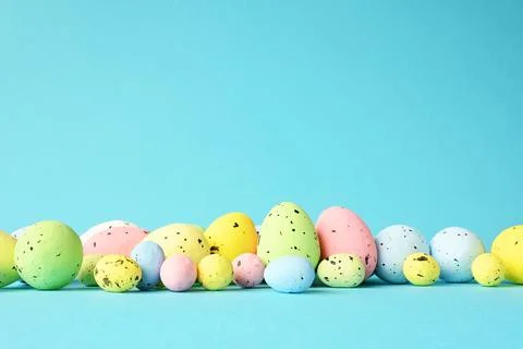 Row of painted colored easter eggs on blue background. Stock Photos