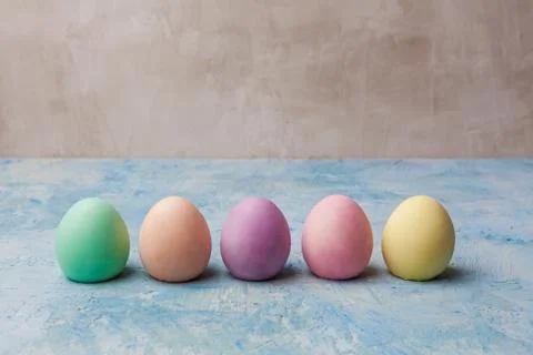 Row of painted easter eggs on painted background with copy space Stock Photos