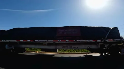 A row of parked semi trucks with loads in a parking lot and shining sun on a  Stock Footage 172422540