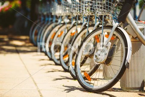Row of parked vintage bicycles bikes for rent on sidewalk Stock Photos