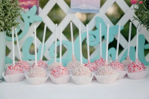 A row of pink and white cake pops with sprinkles on a white stand Stock Photos
