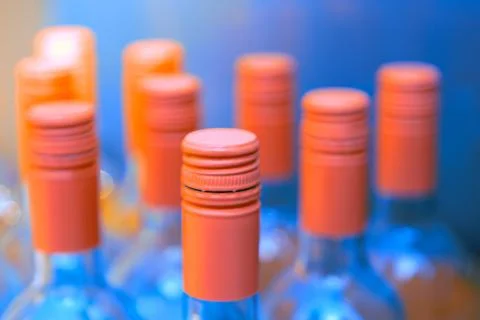 Row of pink wine bottles featuring various colored caps Stock Photos