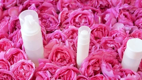 Row Of Plain Cosmetic Bottles  Surrounded By Tender Rose Flowers, Pan Stock Footage 83761314