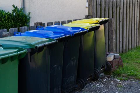 Row of plastic trash cans along the fence. Stock Photos