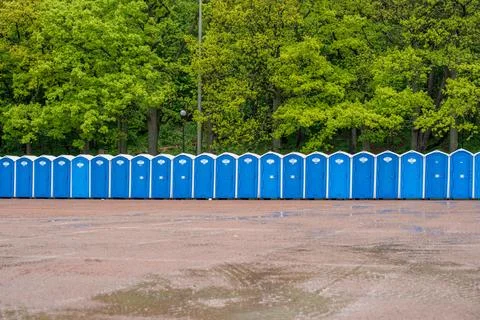 A row of portable toilets in front of a forest. Stock Photos