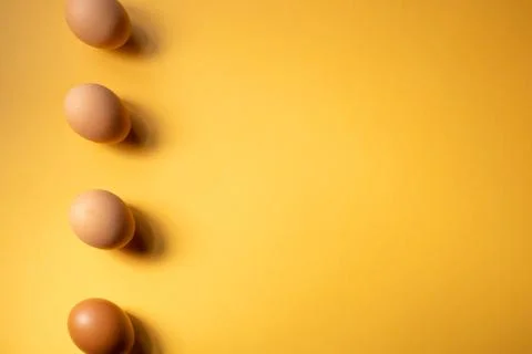 Row of raw eggs aligned on yellow background. Easter concept. Space for text 스톡 사진