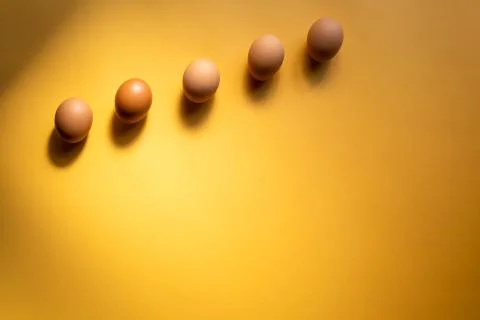 Row of raw eggs aligned on yellow background. Easter concept. Space for text 스톡 사진