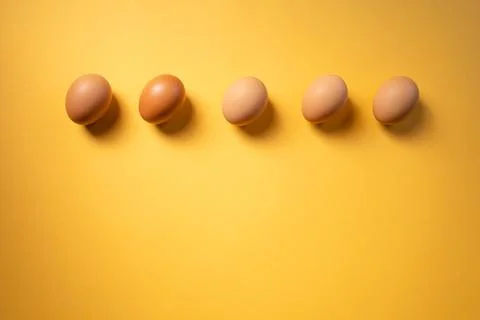 Row of raw eggs aligned on yellow background. Easter concept. Copy space 스톡 사진