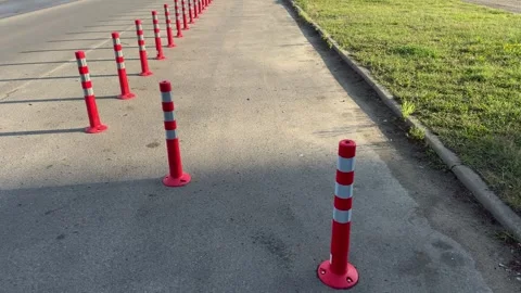 Row of red and white striped traffic bollards on asphalt road Видео 340998138