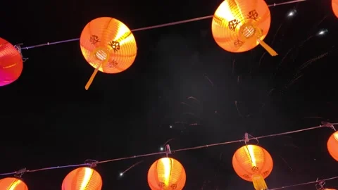 A row of red lanterns hanging from a wire with fireworks 動画素材 325823855