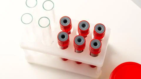 A row of red tubes are lined up on a white surface Stock Photos