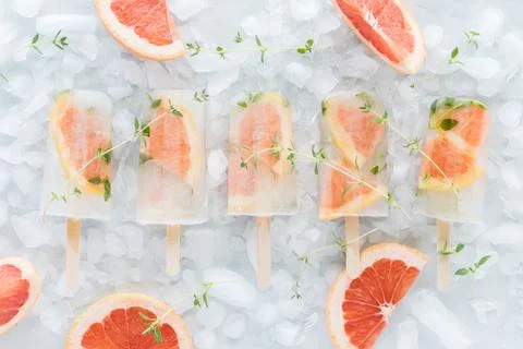 A row of refreshing grapefruit thyme popsicles on a bed of ice. Stock Photos
