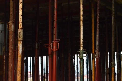 A row of rusty metal posts are lined up in a warehouse.  Stock Photos