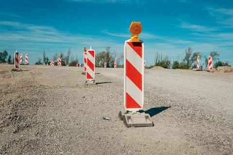 Row of safety barrier posts with orange warning beacons on an unpaved road... Fotos Stock