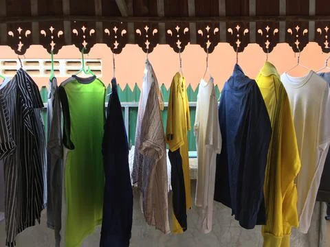 A row of second hand cheap clothes hand drying outdoors under the roof. Stock Photos