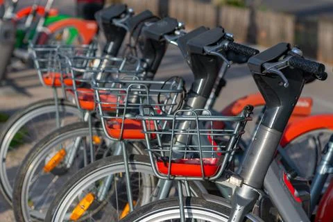 Row of shared bicycles parked along a city street with baskets Foto stock