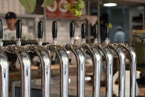 Row of shiny chrome beer taps with black handles at bar counter Stock Photos