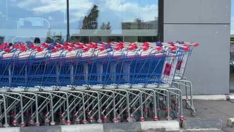Row of shopping carts lined outside supermarket entrance in urban area. Shopping Stock Footage 328352088