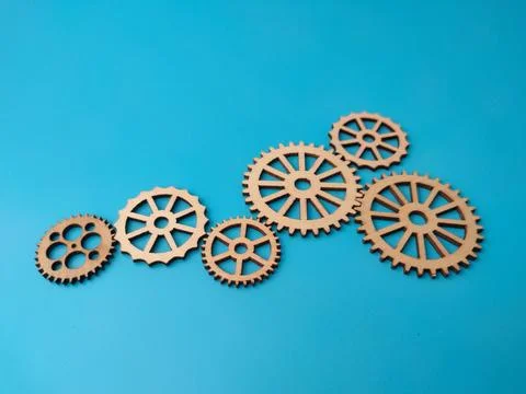 A row of six different sized interlocking wooden gear wheels lies arranged .. Foto stock