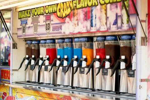 Row of slushie machines with multi-colored frozen drinks at a festival food.. Stock Photos