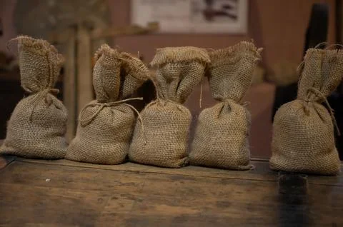 A row of small burlap sacks tied with twine, arranged on a rustic wooden surf Stock Photos