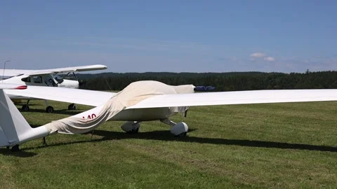 Row of Small Motorized and Glider Aircraft Lined Up on a Mown Grass Stock Footage 327410795