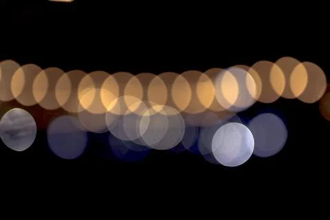 A row of softly blurred night lights creates layered bokeh circles on a dark Stock Photos
