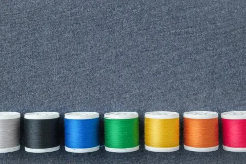 Row of spools of multicolored threads on sewing cloth. View from above. Stock Photos