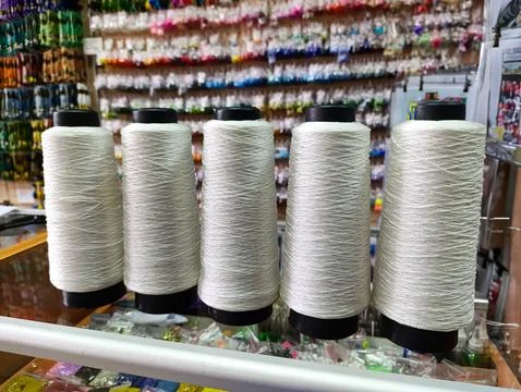 A row of spools of thread on a shelf in a store Stock Photos