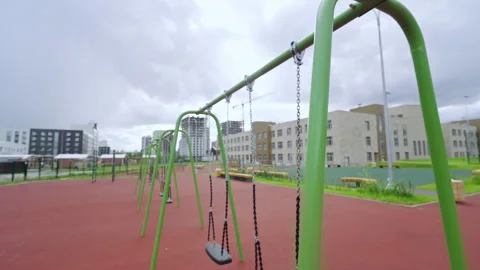 Row of swings stands on rubber surface of school playground Stock Footage 334711517
