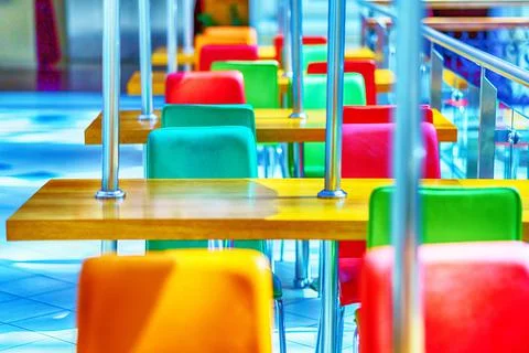 A row of tables and bright multi-colored chairs on a sunny day in the restaur Stock Photos