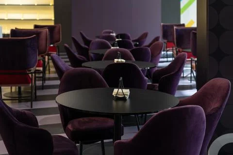 A row of tables with soft comfortable violet chairs for visitors to the food  Stock Photos