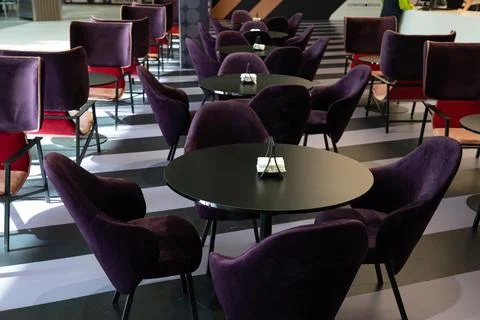 A row of tables with soft comfortable violet chairs for visitors to the food  Stock Photos