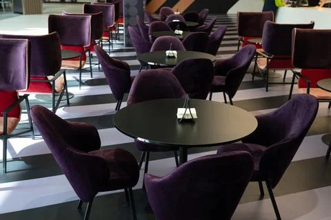 A row of tables with soft comfortable violet chairs for visitors to the food  Фото