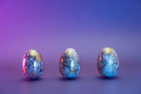 Row of three Easter golden eggs with different patterns in neon colors light Stock Photos