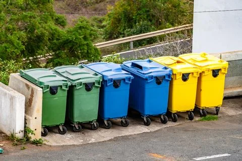A row of trash cans are lined up on the side of the road Stock Photos