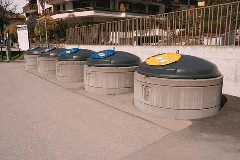 A row of trash cans are lined up on the sidewalk Stock Photos