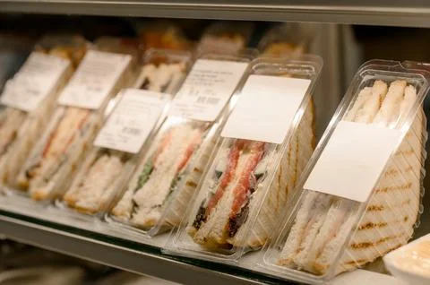 A row of triangular sandwiches in clear plastic packaging on a store display Stock Photos
