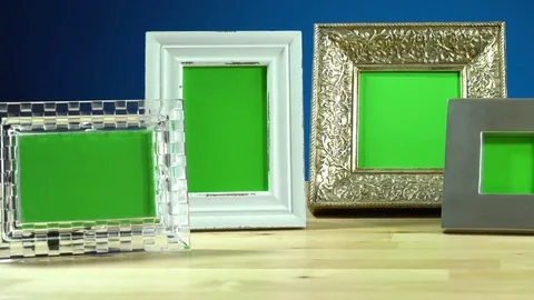 Row of various photo frames with green screen on elegant table interiors disp Stock Footage