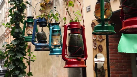 A row of vintage, rustic, multi-colored kerosene lamps hang in a row and swaying Stock Footage 288107721