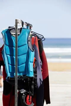 A row of wetsuits hanging on a rack at a surf school. portrait image Stock Photos