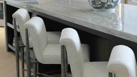 Row of white bar stools with gray legs standing next to reflective marble dining Stock Footage 265201378