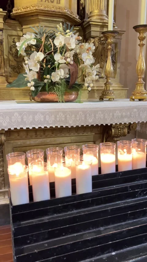 Row of white devotional candles burning in glass holders inside historic church Stock Footage 326465582